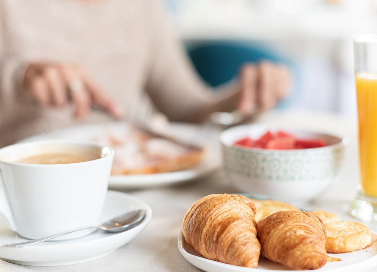 Colazione con croissant, caffè, succo d'arancia e una ciotola di frutta.