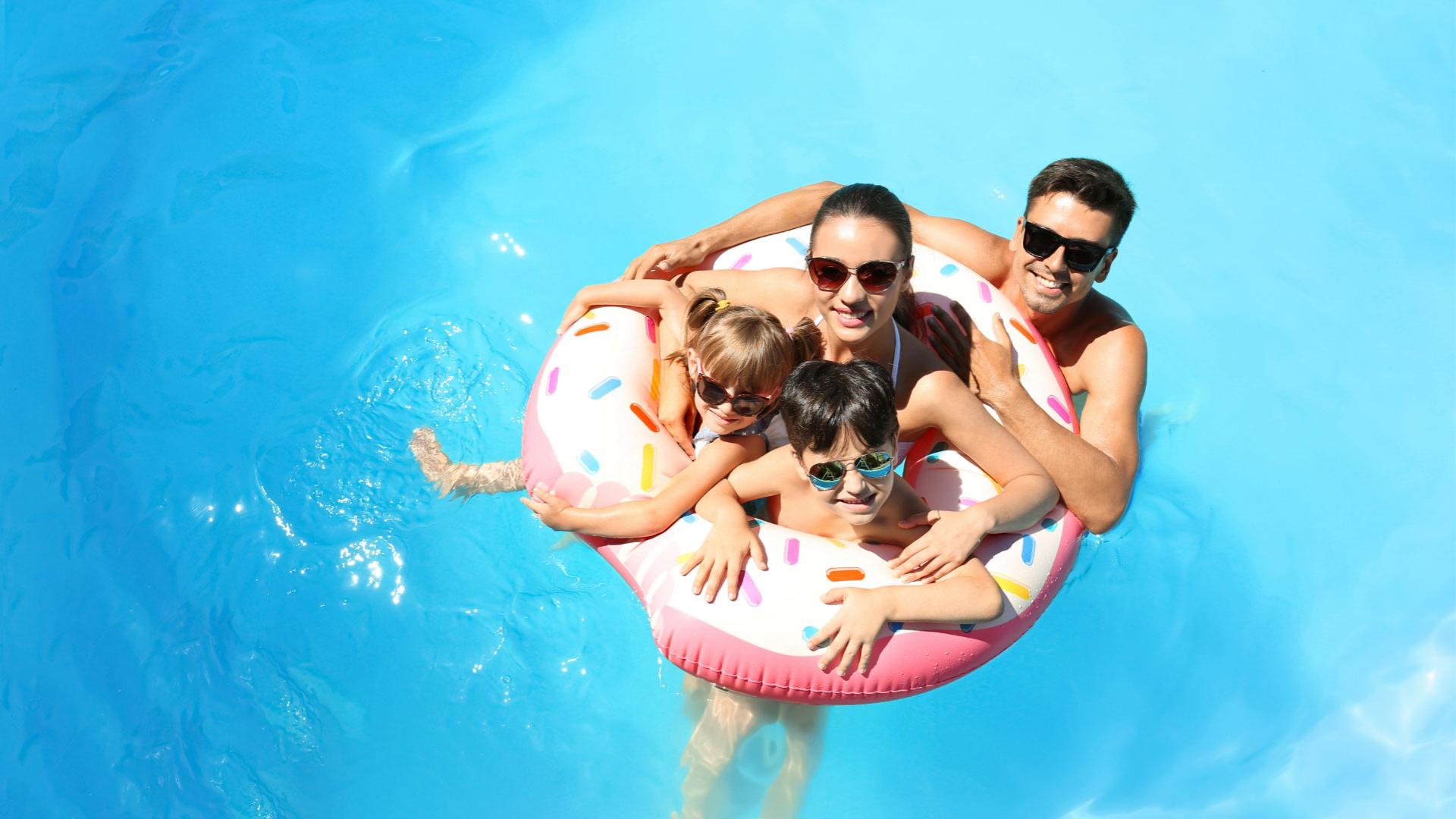 Famiglia felice in piscina con un salvagente a forma di ciambella.