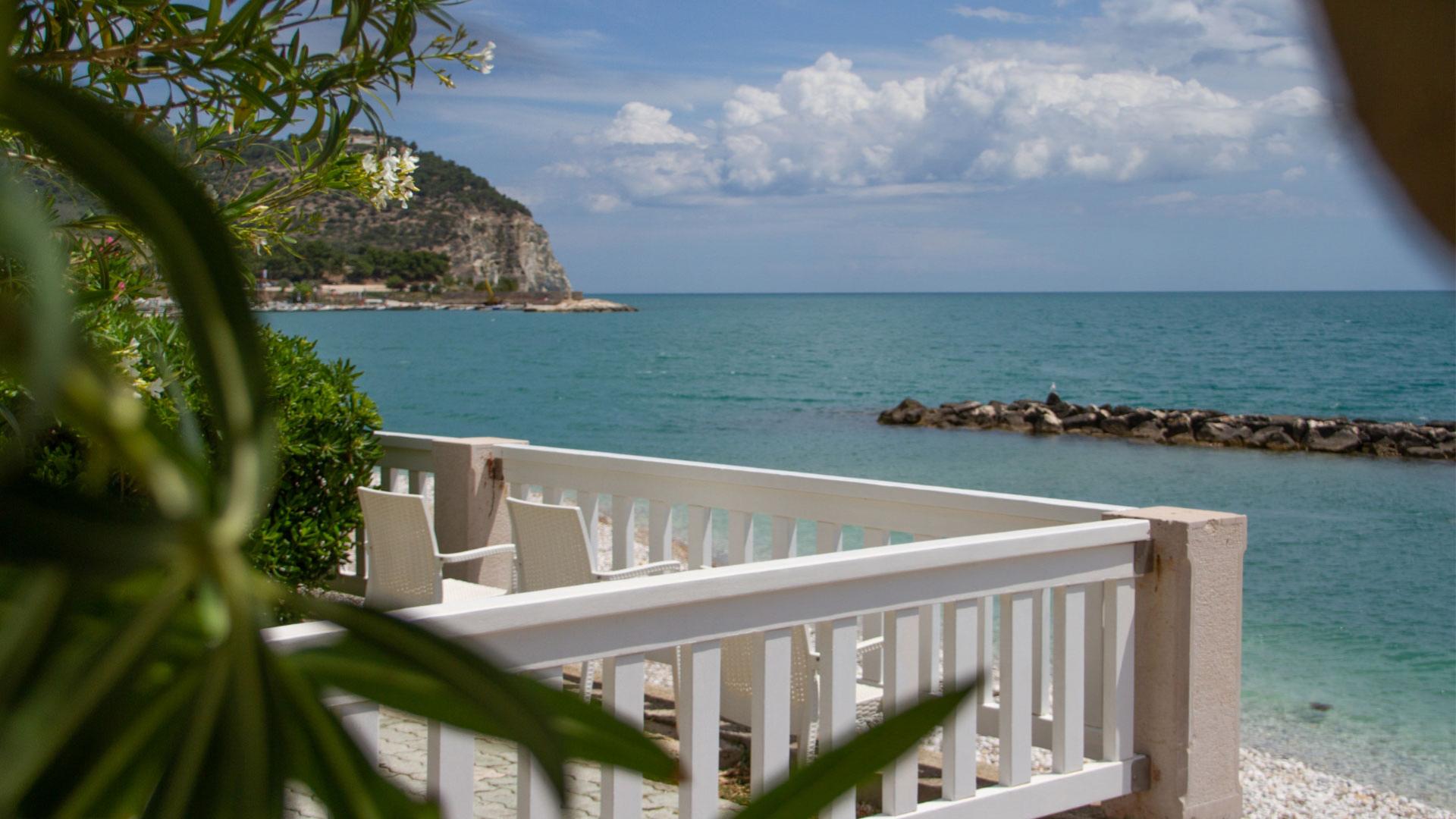 Terrazza sul mare con vista su una scogliera e cielo nuvoloso.