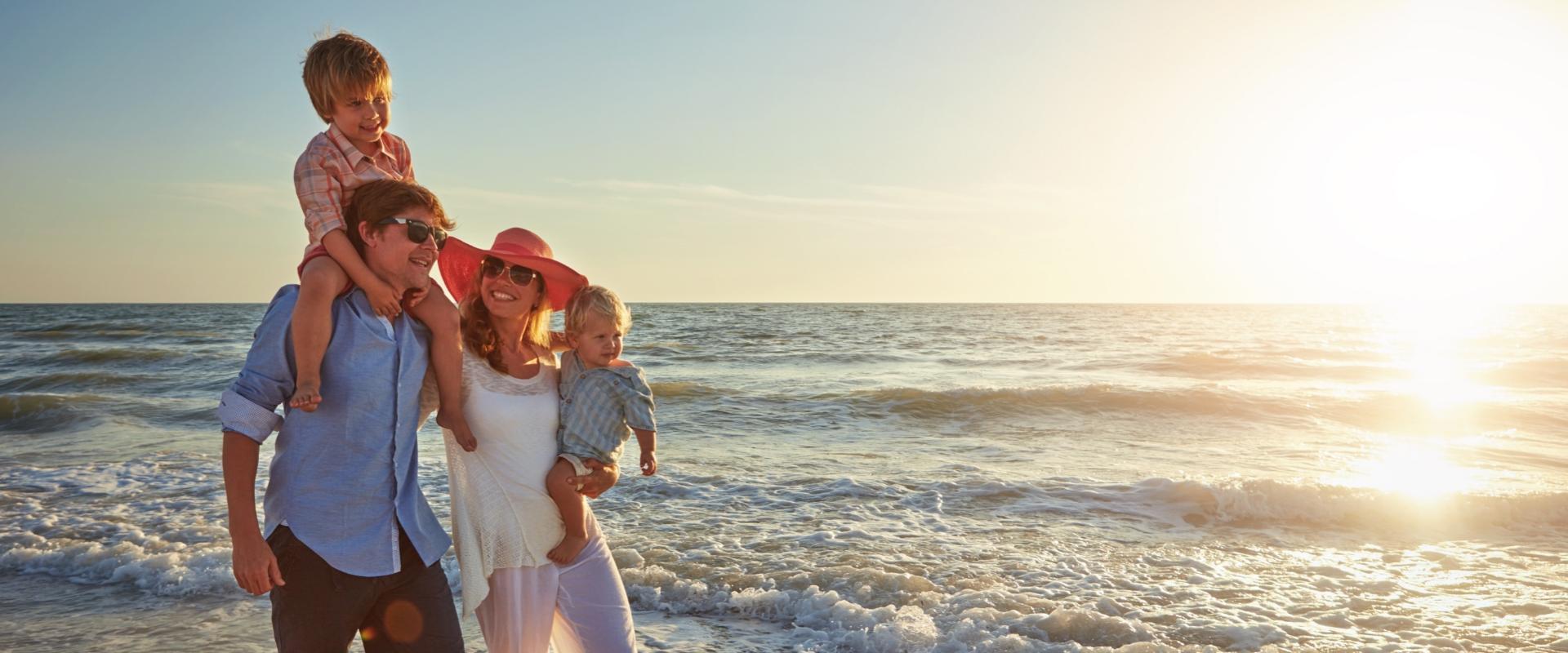 Famiglia felice che cammina sulla spiaggia al tramonto, godendosi il tempo insieme.